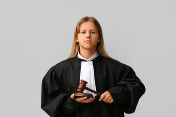 Portrait of teenage judge with gavel on grey background