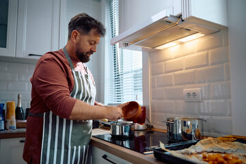 Mature man cooking in kitchen.