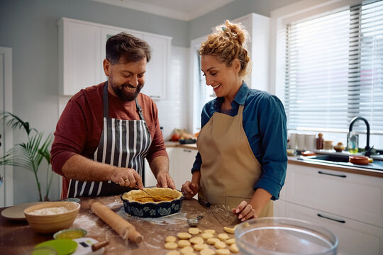 Happy couple making pumpkin pie while backing in  kitchen.