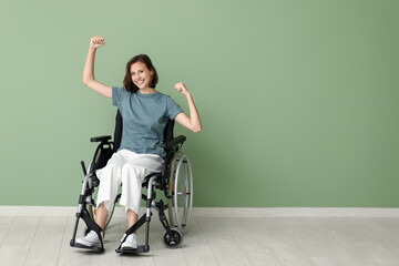 Young pretty woman in wheelchair resting near green wall at home