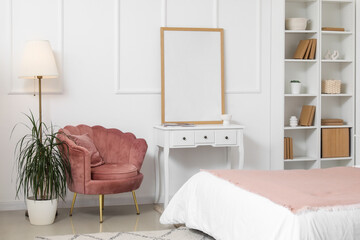 Stylish bedroom with cozy armchair, bed and shelving unit