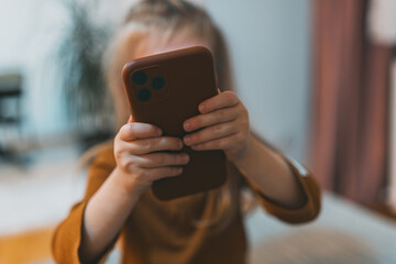 A little girl holds up a smartphone, possibly taking a picture. Her curiosity and innocence are evident as she engages with the modern digital world around her.