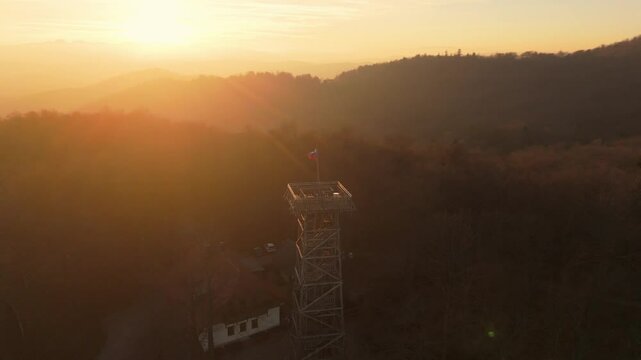 Stolp Planina, Planina Tower above Vrhnika near Ljubljana, Slovenia, with waving slovenian flag in tha autumn sunset, drone video, aerial shots
