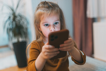 A girl intently observes a smartphone, illustrating deep concentration and interaction with...