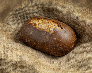 closeup view of a rustic loaf of bread with a cracked crust displayed on a burlap cloth