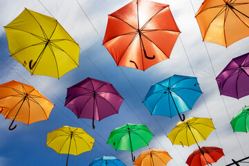 Umbrellas with different colors, urban installation, low-angle view against sunny sky with clouds