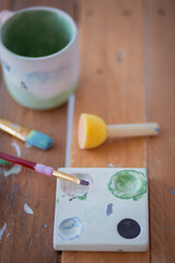 Many sizes brushes and sponges on an artist palette on a wooden surface