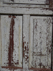 Close-up of old wooden door with old paint cracking and peeling off. Peeled paint flakes on wood