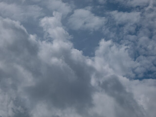 View of blue sky with fluffy white clouds in a sunny day. Dark sky sunlit with beautiful white clouds