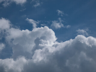 View of blue sky with fluffy white clouds in a sunny day. Dark sky sunlit with beautiful white clouds