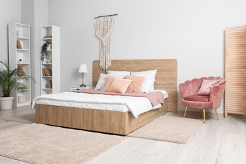 Stylish interior of bedroom with cozy bed, comfortable armchair