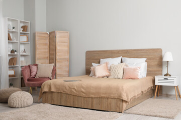 Modern interior of bedroom with comfortable bed, cozy armchair and shelving unit