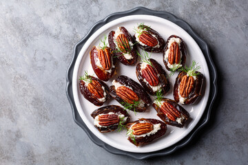 A plate with Stuffed Dates with goat cheese, mayonnaise, pecan nuts. Festive appetizers, Grey table...