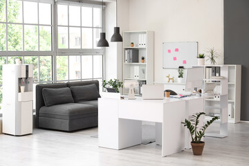 Interior of modern office with workplace, couch and shelf units