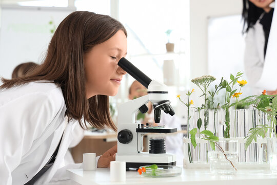 Teenage girl looking through microscope in Biology class, closeup