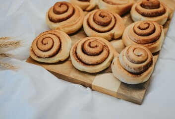 Fresh cinnamon on a wooden tray before applying buttercream on a white fabric background