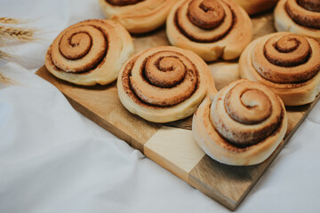 Fresh cinnamon on a wooden tray before applying buttercream on a white fabric background