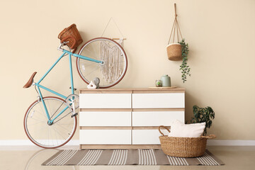 Chest of drawers and bicycle near beige wall in room