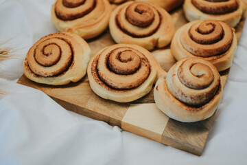 Fresh cinnamon on a wooden tray before applying buttercream on a white cloth background