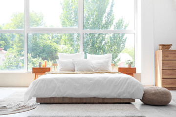 Fototapeta premium Bedroom with big bed, large window, bedside tables and pouf