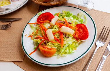 Tasty vegetable salad from fresh lettuce with tomato slices, red onion, grated carrot and pickled asparagus