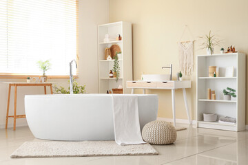 Bathtub with towel, sink and shelving units in interior of bathroom