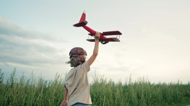 Unrecognizable 5 years old child boy running with wooden vintage airplane. Kid dreaming to be pilot. Imagination freedom, travel everywhere, active childhood