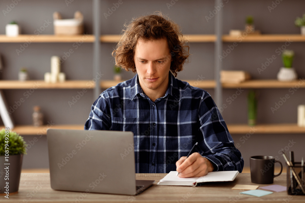 Poster Serious Man Taking Notes Writing Project Ideas In Notebook Sitting At Laptop Computer In Modern Office. Businessman Making Business Report At Workplace Indoor. Entrepreneurship Career Concept