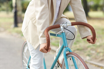 Young businesswoman riding bicycle in city park