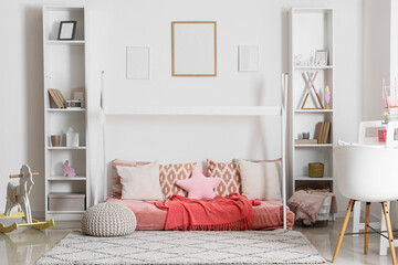 Interior of light children's bedroom with cozy bed, rocking horse and shelving units