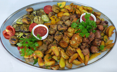 kebab, potato wedges and grilled vegetables on a large platter