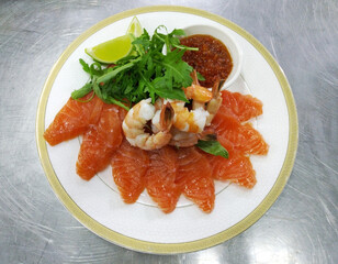 seafood assortment with greens and a slice of lemon. salmon fillet, shrimp and red caviar on a large white plate. restaurant serving of a gourmet dish.