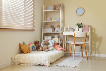 Interior of cozy children's room with shelving unit, workplace and many toys on bed