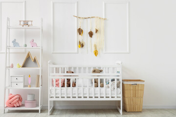 Cute toys in crib with shelving unit and wooden basket near white wall