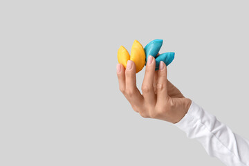 Female hand holding colorful fortune cookies on grey background, closeup