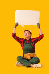 Young female construction worker holding blank speech bubble on yellow background. Woman in male...