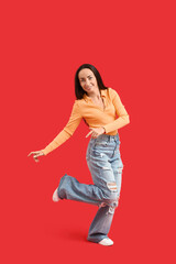 Fototapeta premium Happy middle-aged woman dancing on red background