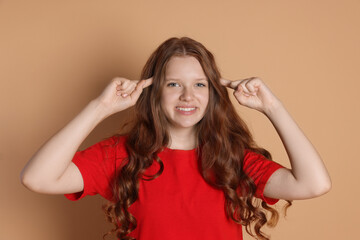 Smiling teenage girl gesturing on beige background