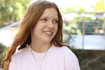 Portrait of happy teenage girl with long hair outdoors