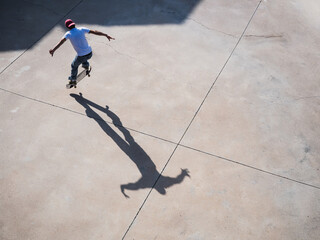 Skateboarder performing a high jump with vivid shadow on concrete