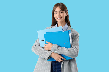 Obraz premium Young businesswoman with folders on blue background