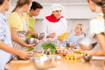During lesson at cooking course, man cook with egg tray in hands tells children about rules of cooking fluffy pancakes