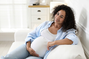 Portrait of beautiful pregnant woman on sofa at home