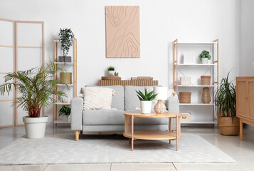 Interior of light living room with grey sofa, shelf units and plants © Pixel-Shot