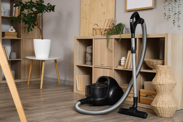 Vacuum cleaner near shelf unit in living room interior