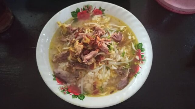 A warm bowl of soto ayam being enjoyed, showcasing rich broth, shredded chicken, fresh herbs, and comforting Indonesian flavors.