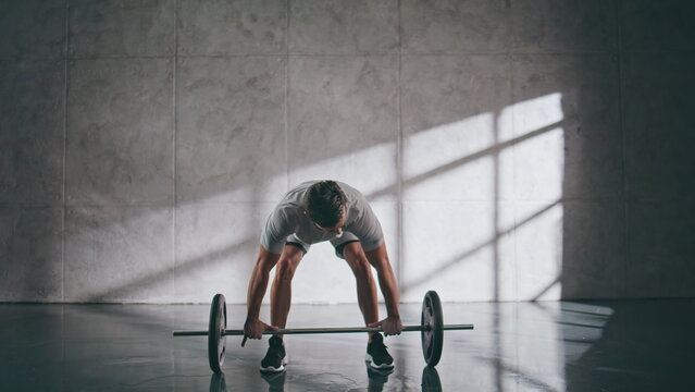 Muscular sportsman lifting weights in gym. Sporty powerlifter fitness workout