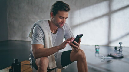 Sport man checking cellphone relaxing fitness closeup. Athlete taking break