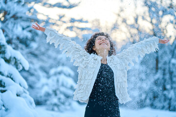 A woman happily playing with snow in a snow-covered winter forest