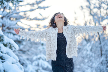 A woman happily playing with snow in a snow-covered winter forest